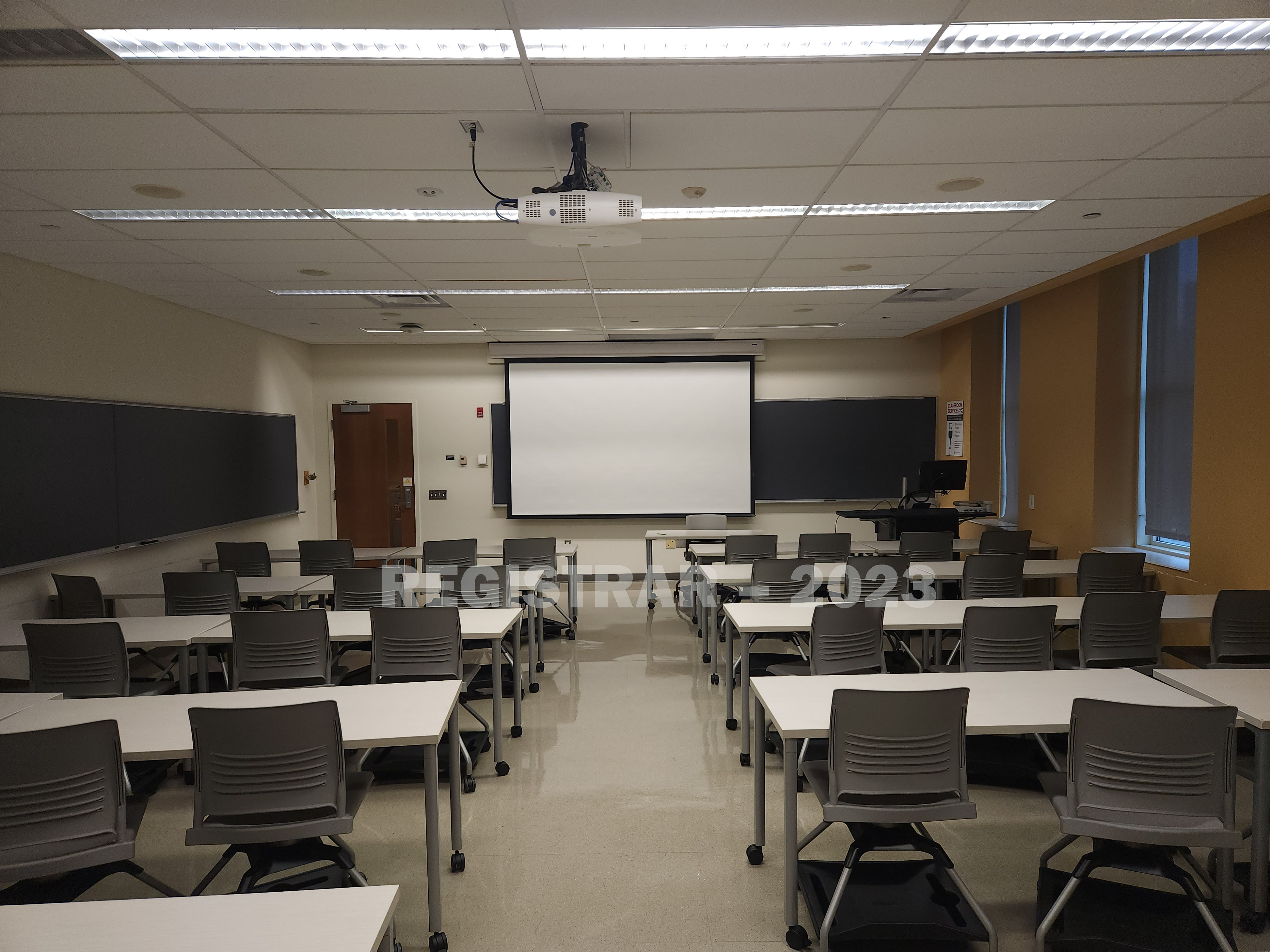 Jennings Hall room 140 view from the back of the room with projector screen down