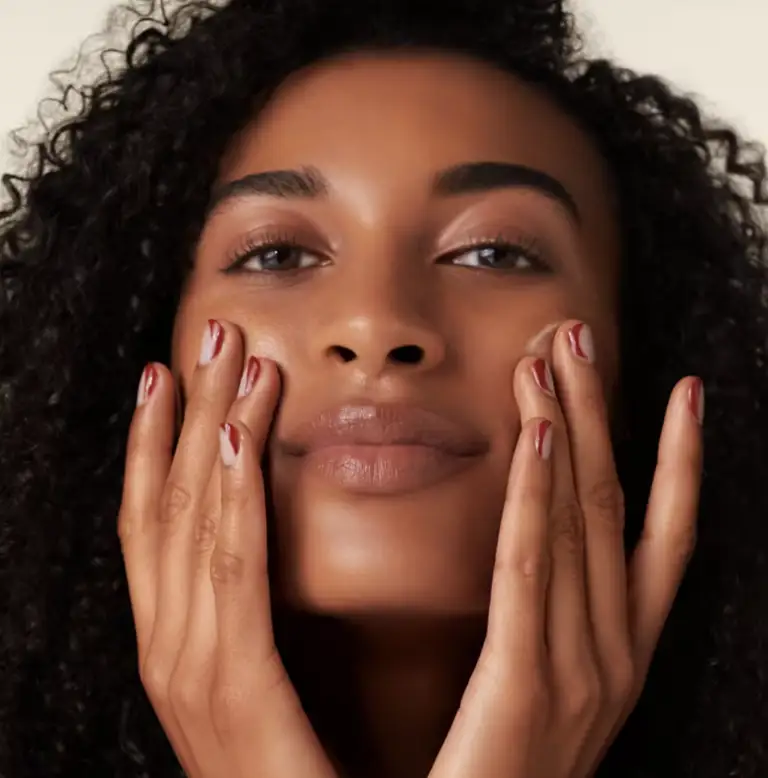 a close up of a woman 's face with her hands on it