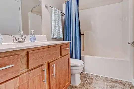 full bathroom featuring tile floors, mirror, toilet, oversized vanity, shower curtain, and shower / bath combination