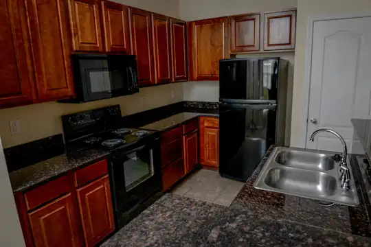 kitchen with tile floors, refrigerator, electric range oven, microwave, dark brown cabinetry, and dark stone countertops