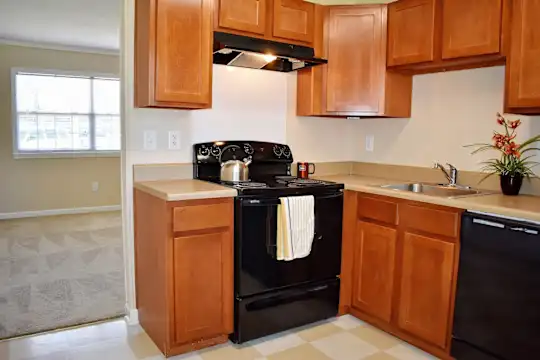 kitchen featuring natural light, electric range oven, dishwasher, exhaust hood, light countertops, light tile floors, and brown cabinetry