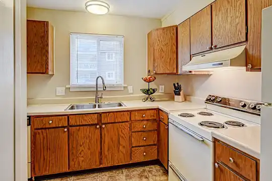 kitchen featuring natural light, electric range oven, extractor fan, light tile floors, brown cabinets, and light countertops