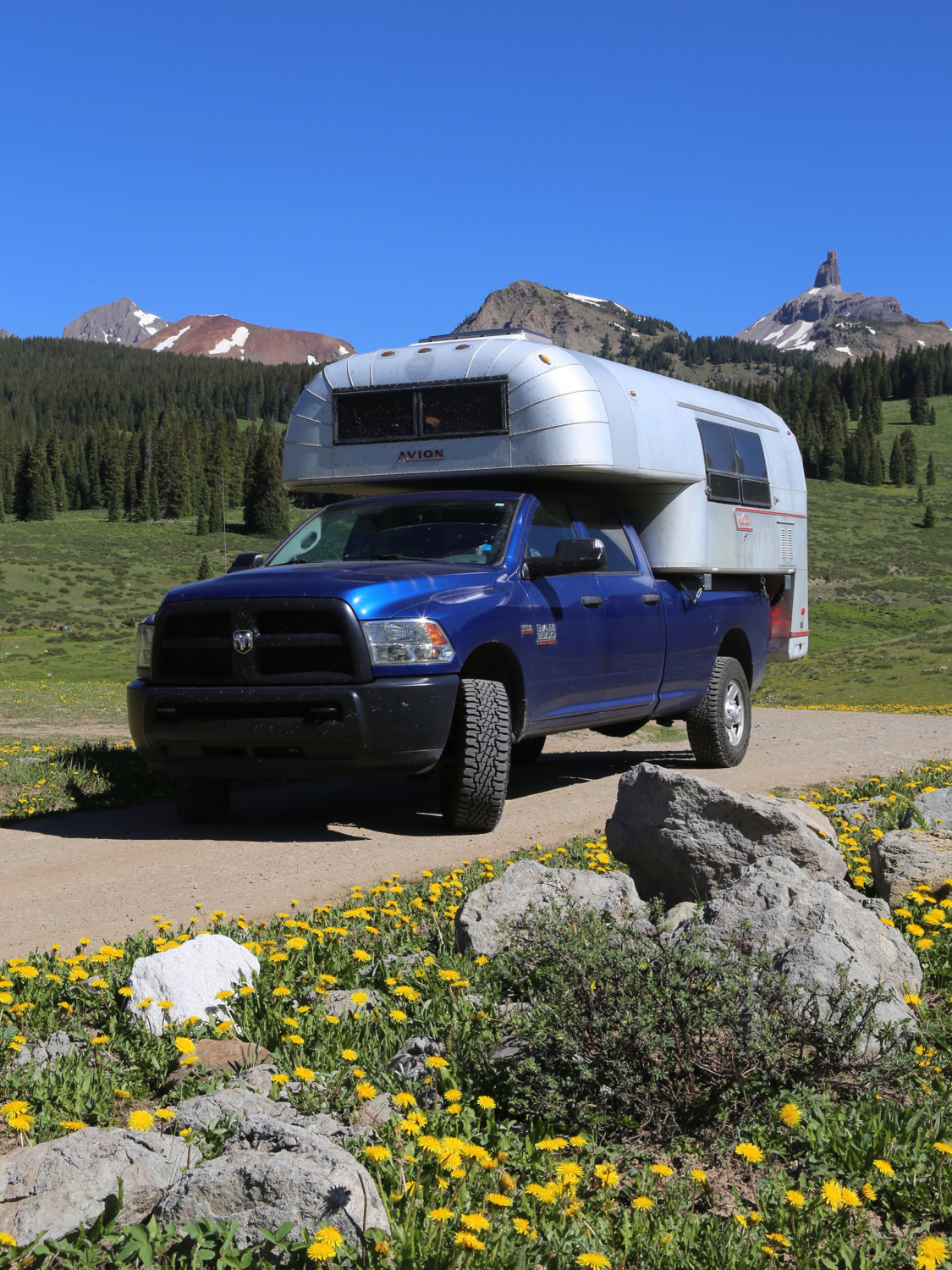 Vintage truck camper on a blue truck on a dirt road in the Colorado wilderness