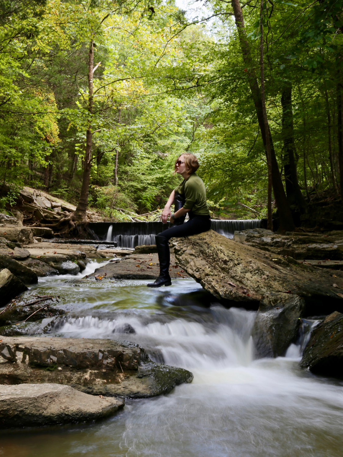 Woman sitting over a shady creek.