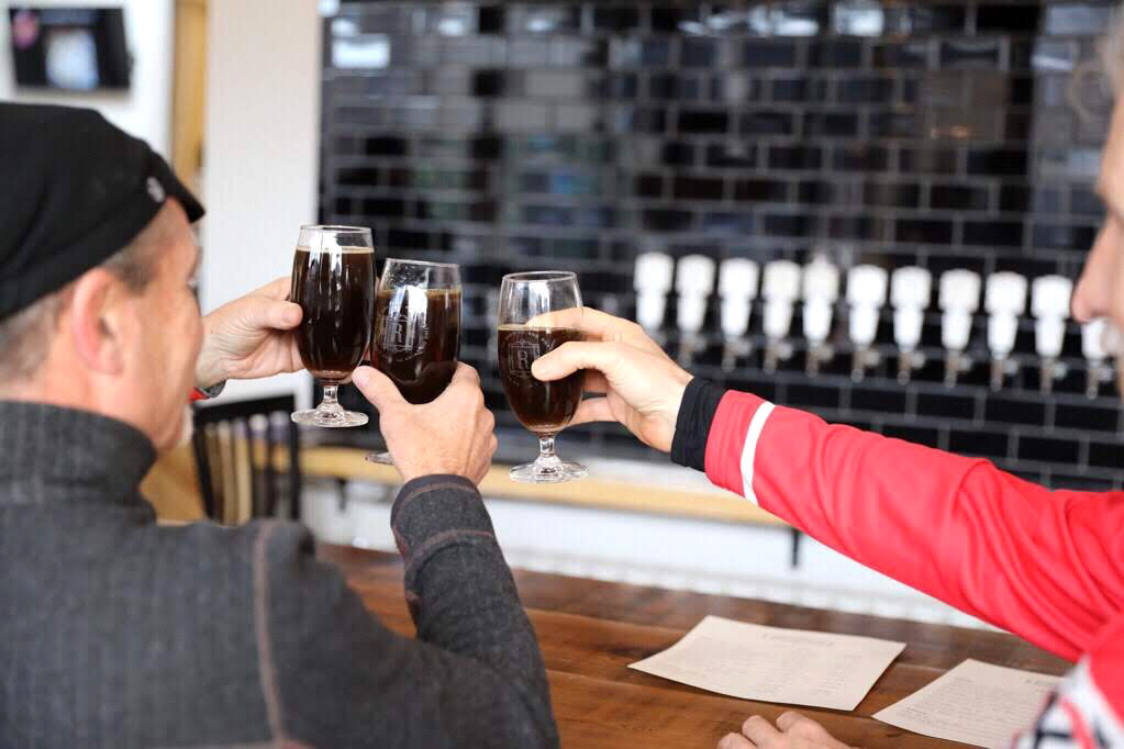 People gathered around bar counter clinging beer glasses together