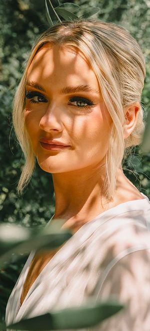 Bride wearing blonde hair in stylish updo with natural wedding makeup with long black eyelashes