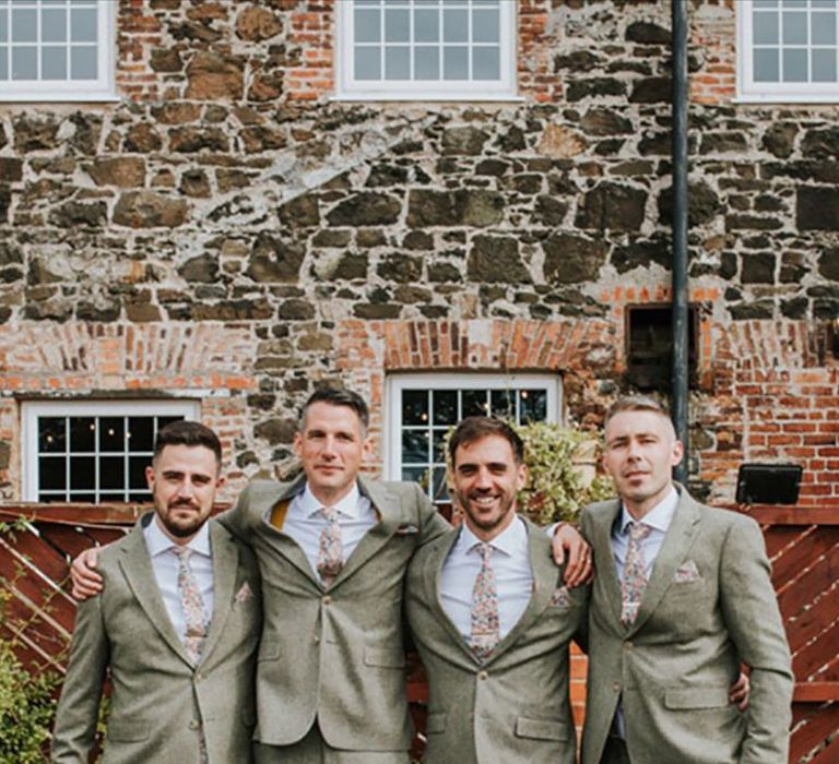 Groom and groomsmen in floral patterned ties with light green wedding suits 