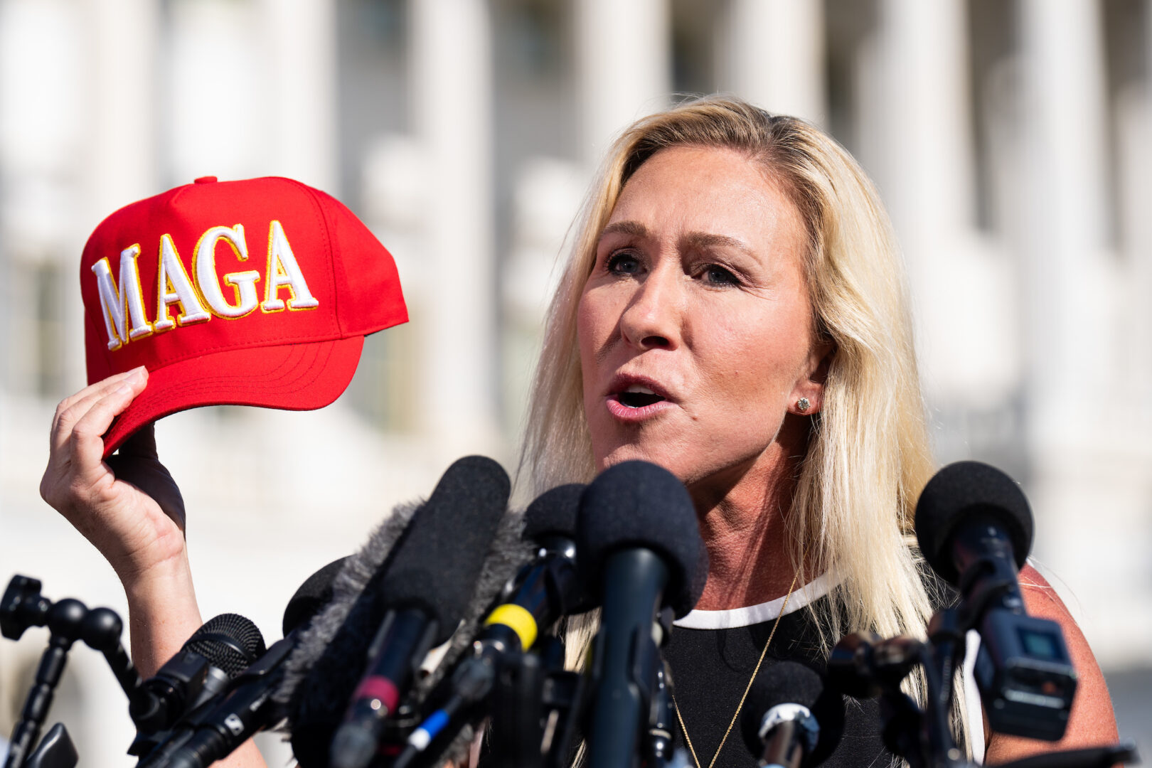 Rep. Marjorie Taylor Greene, R-Ga., holds her “Make America Great Again” hat during the news conference outside the Capitol on May 1. 