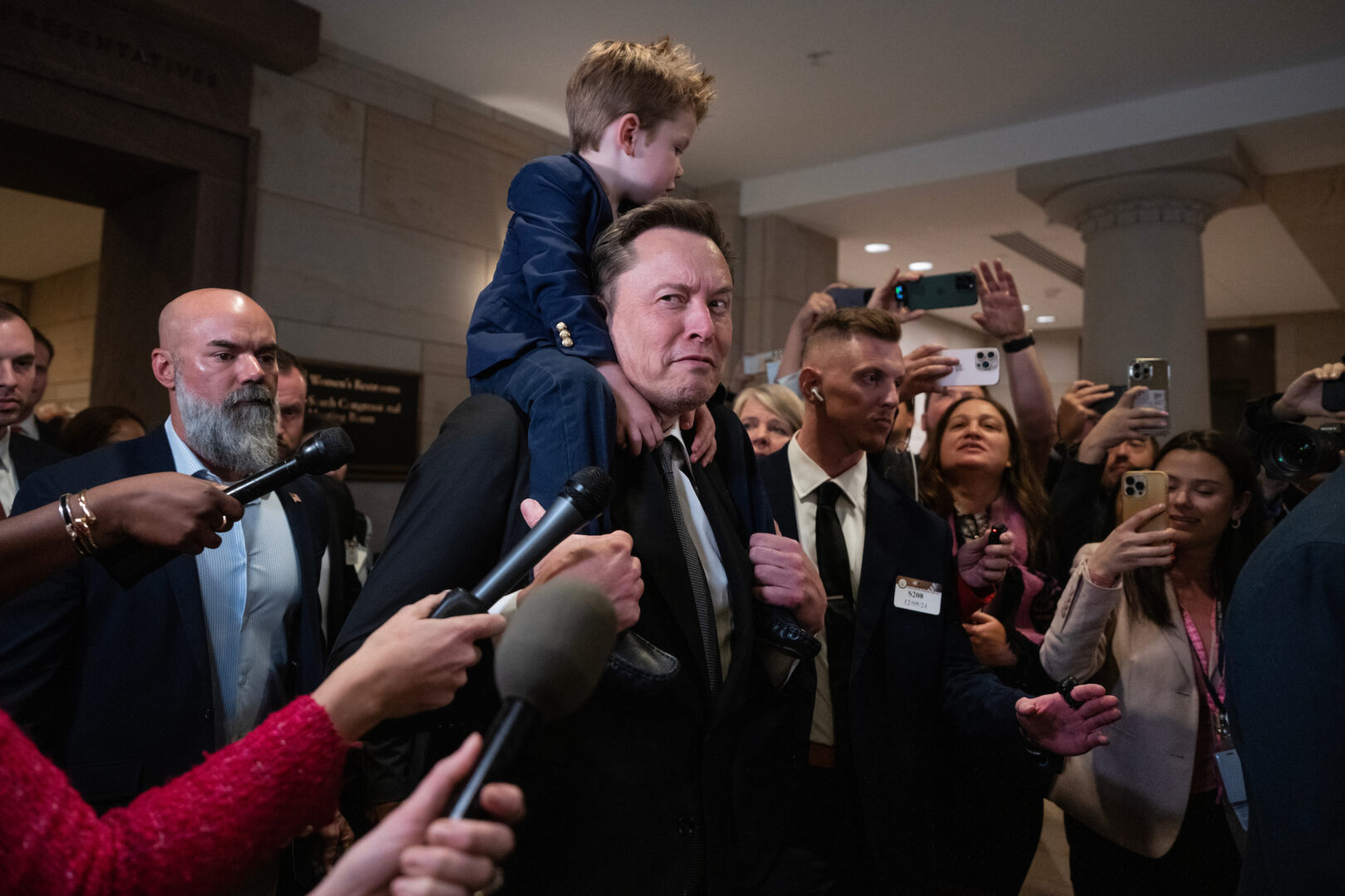 Elon Musk, with his son, makes his way to a meeting in the Capitol Visitor Center with House and Senate Republicans to talk about President-elect Donald Trump's "Department of Government Efficiency," on Thursday. Vivek Ramaswamy also attended.