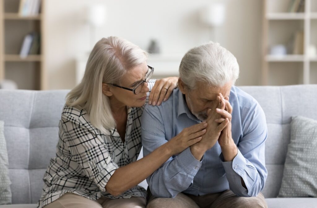 A person embraces and consoles a senior suffering from hallucinations.