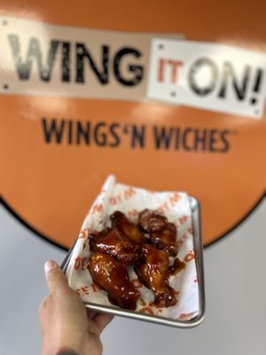 Photo of Wing It On! - Waterbury, CT, US. a hand holding a tray of wings