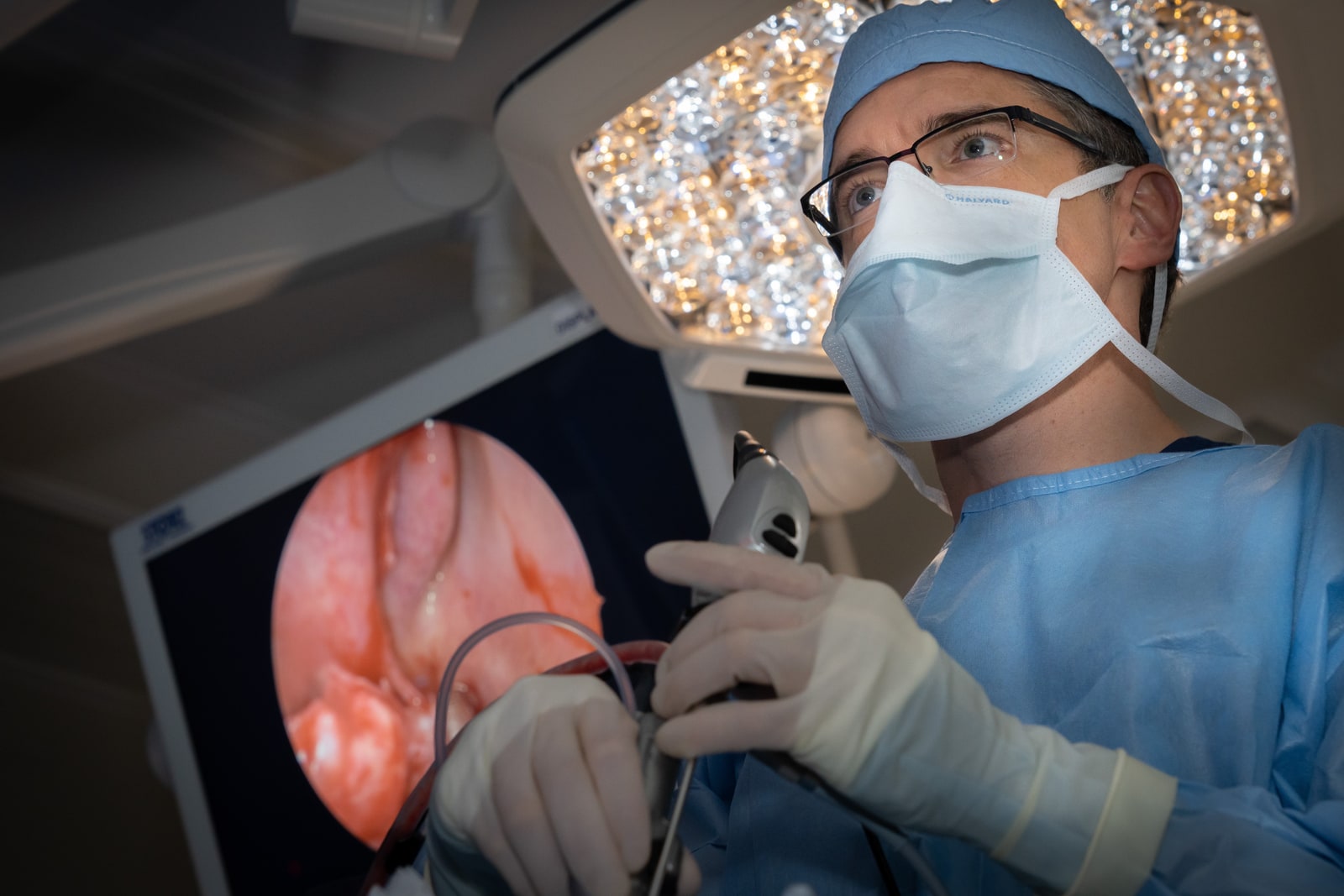 Dr. Ryan performing endoscopic nasal surgery with a monitor showing internal view.