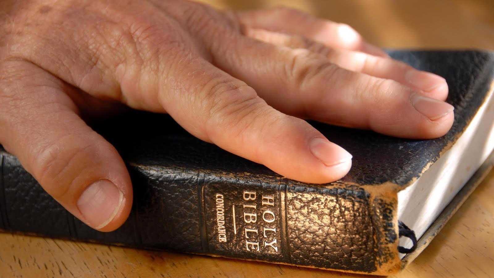 Hand on Bible on Table