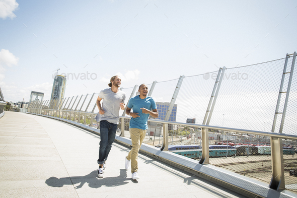 Two young men jogging along a bridge.