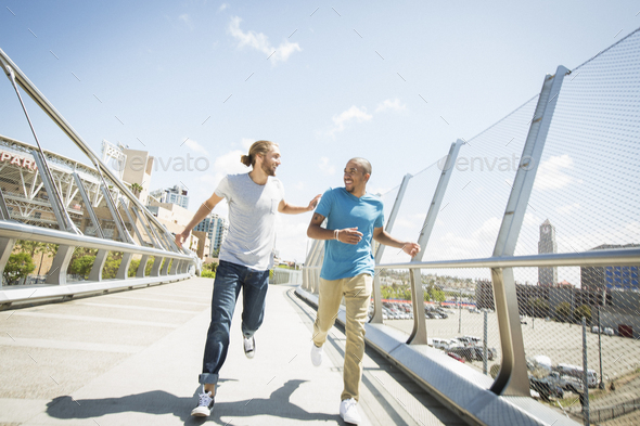 Two young men jogging along a bridge.