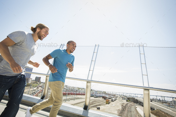 Two young men jogging along a bridge.