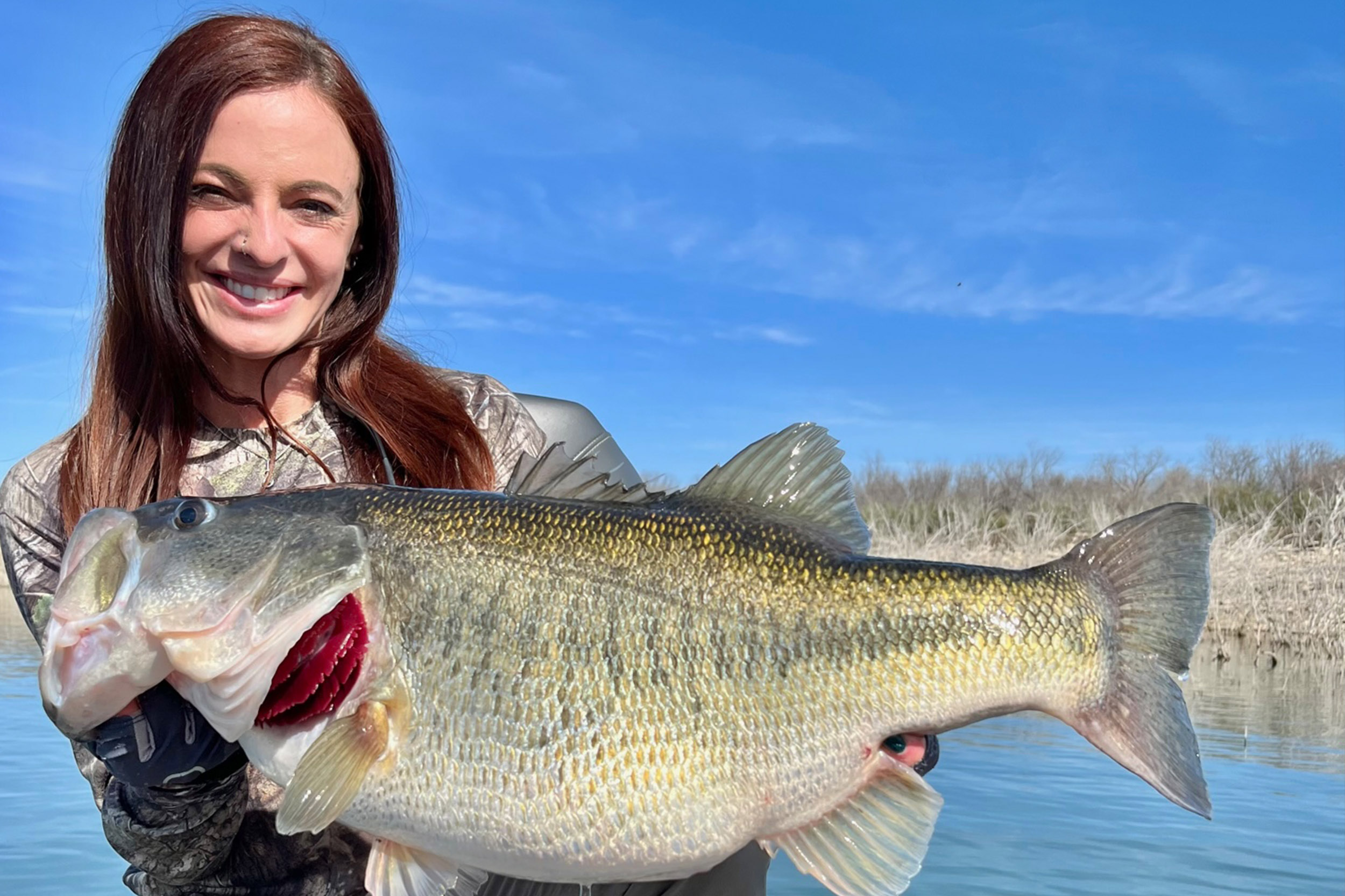 a woman poses with a large fish