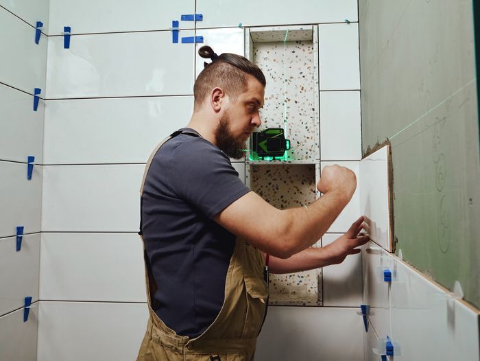 A man placing tiling over a cement backerboard.