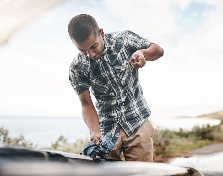 Man checking oil on his vehicle's dipstick