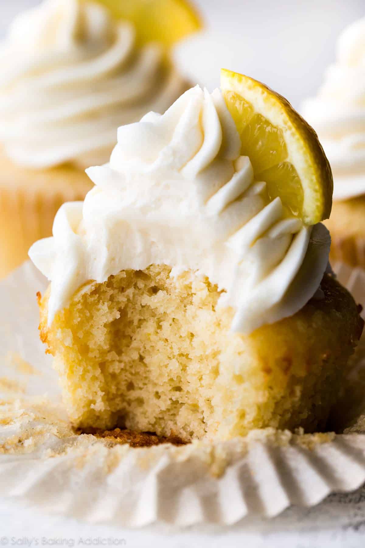 lemon cupcake topped with vanilla buttercream and a lemon slice with a bite taken from it