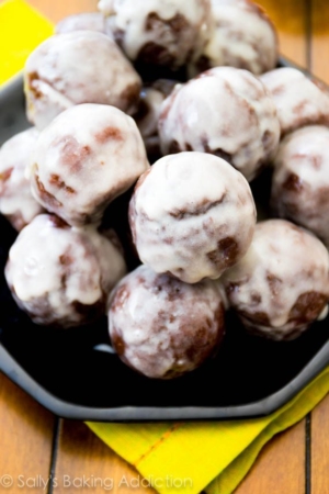 stack of glazed chocolate donut holes on a black plate