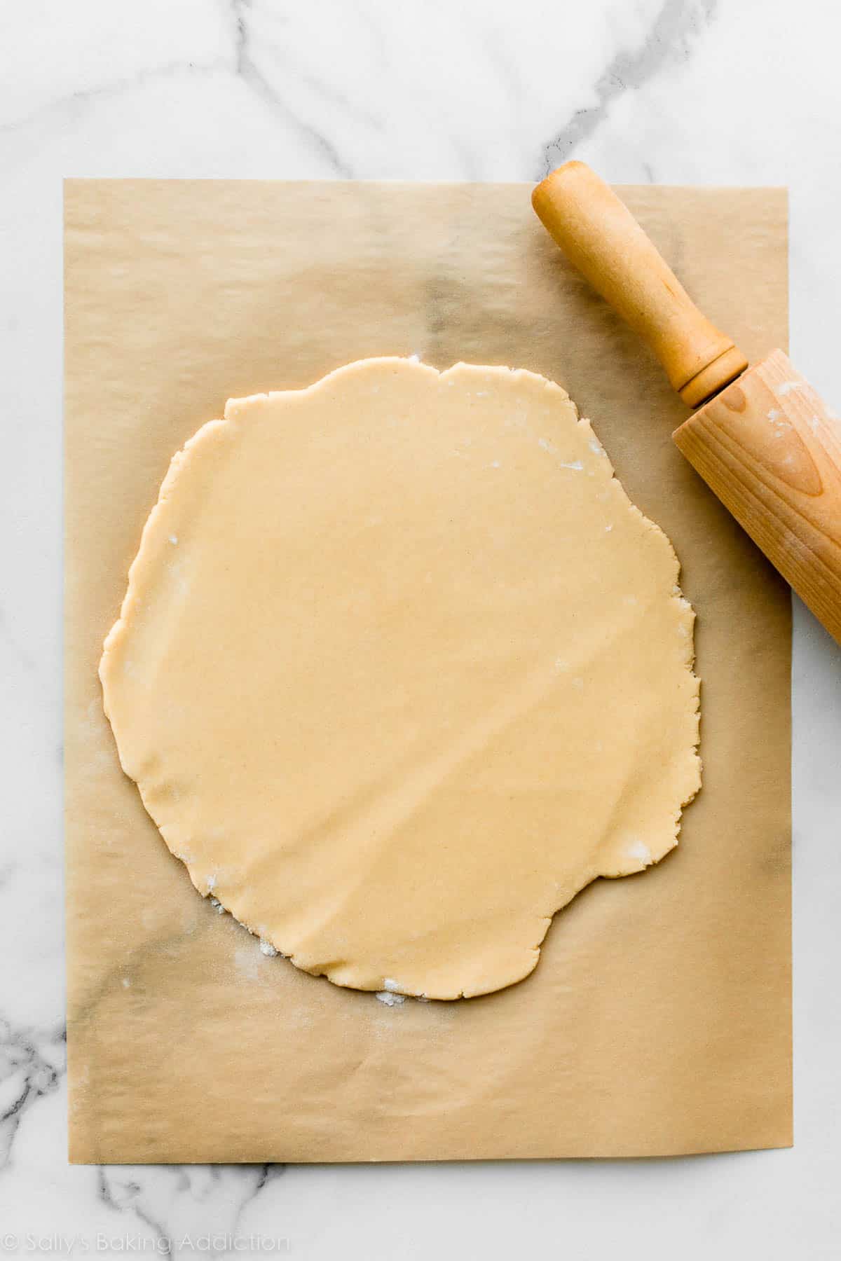 rolled out sugar cookie dough on brown parchment paper.