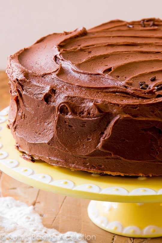 marble layer cake with milk chocolate frosting on a yellow cake stand