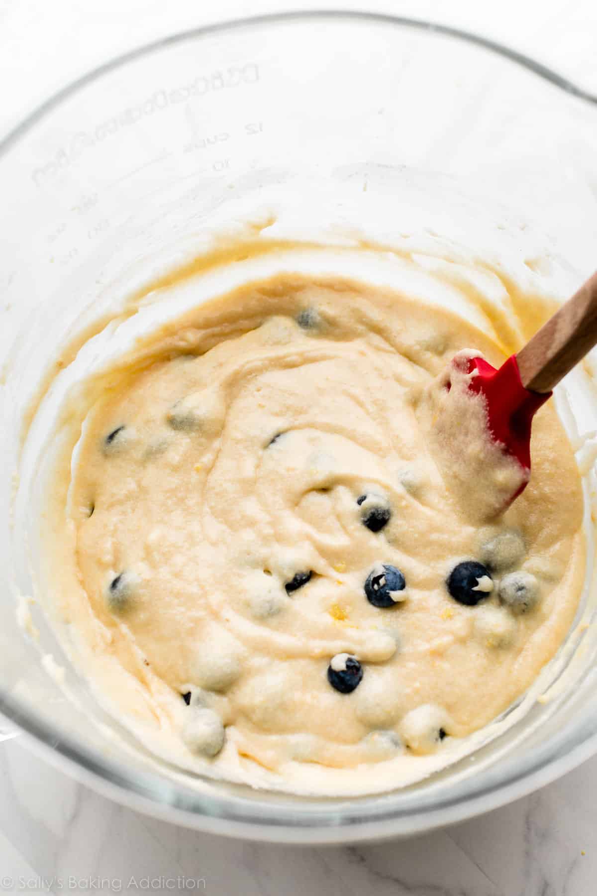 lemon blueberry batter in glass bowl on marble countertop.