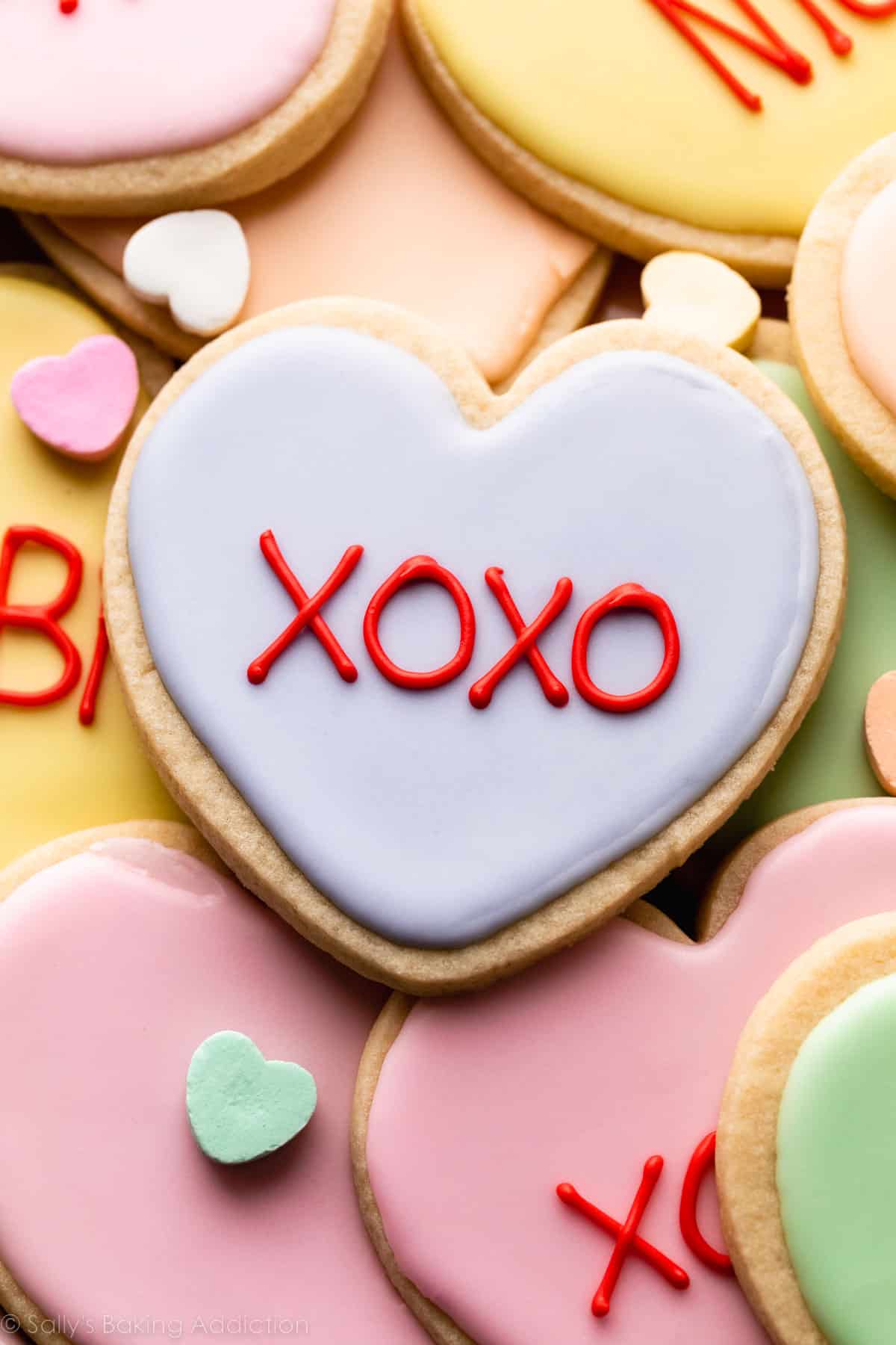 close-up of heart-shaped Valentine's Day cookie decorated with pastel purple royal icing with xoxo piped on top.