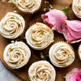 overhead image of vanilla wedding cupcakes with champagne frosting and gold sprinkles on wood server