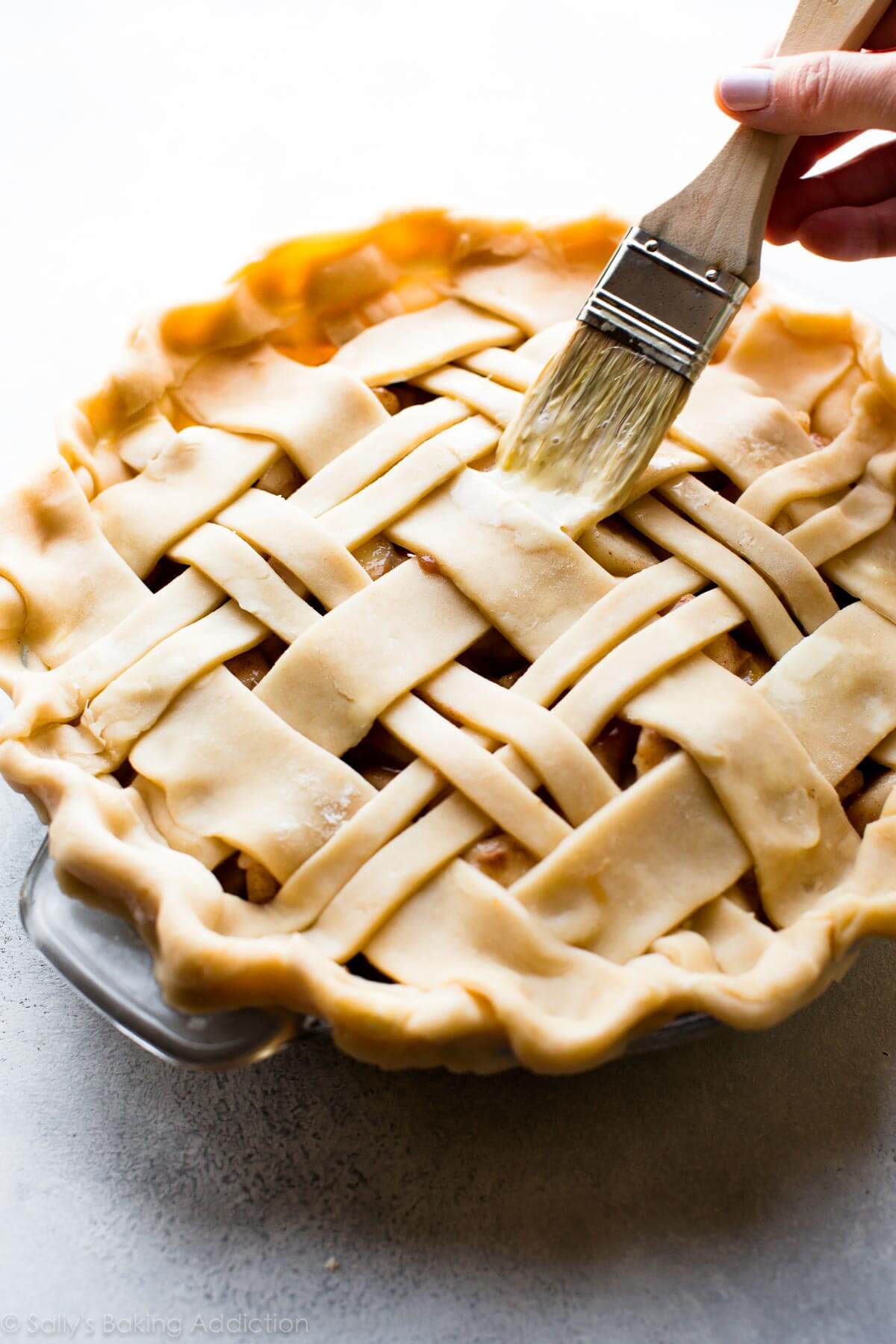 brushing egg wash onto lattice pie crust before baking