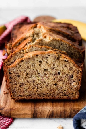 homemade banana bread slices on wooden cutting board.