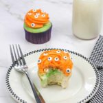 A monster eyeball cupcake on a plate with a fork.