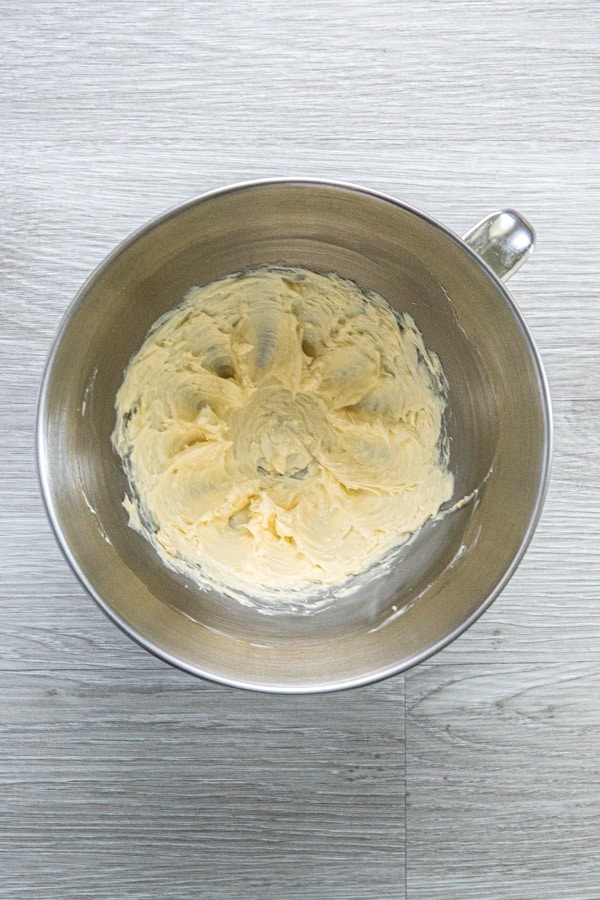 A stainless steel bowl with butter and powdered sugar creamed together.