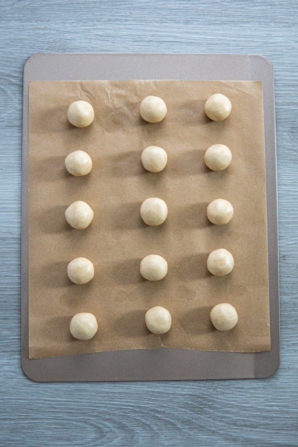 Snowball cookie dough rolled into balls on a cookie sheet.