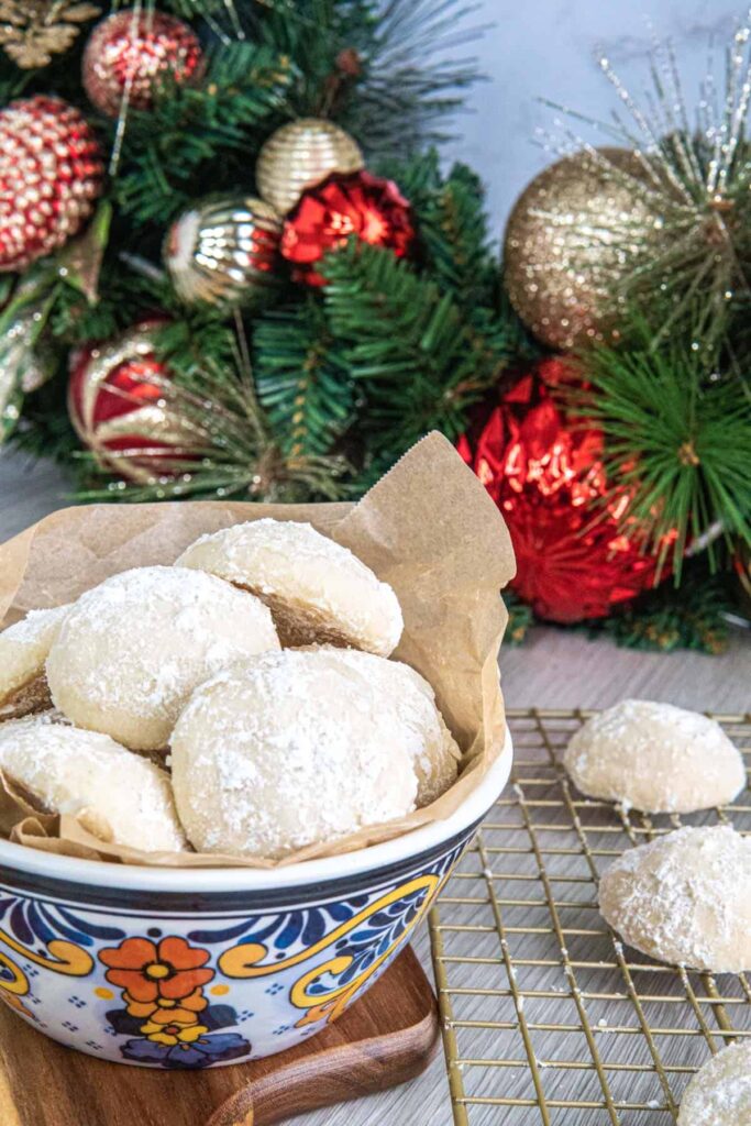 Snowball cookies in a bowl with Christmas decorations in the background.