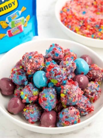 Candy coated grapes dipped in crushed hard candy served in a white bowl.