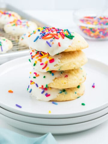 A stack of funfetti cake mix cookies with frosting and rainbow sprinkles.