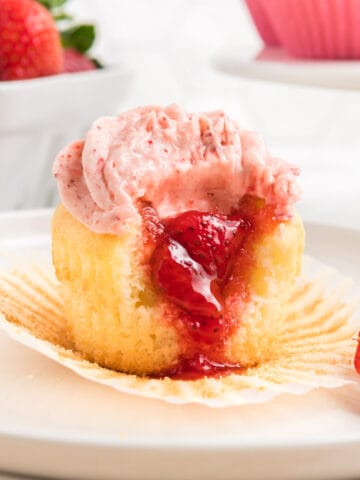 A cupcake with strawberry filling and cream cheese frosting.