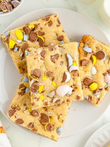 Four mini egg cookie bars stacked on a white plate.