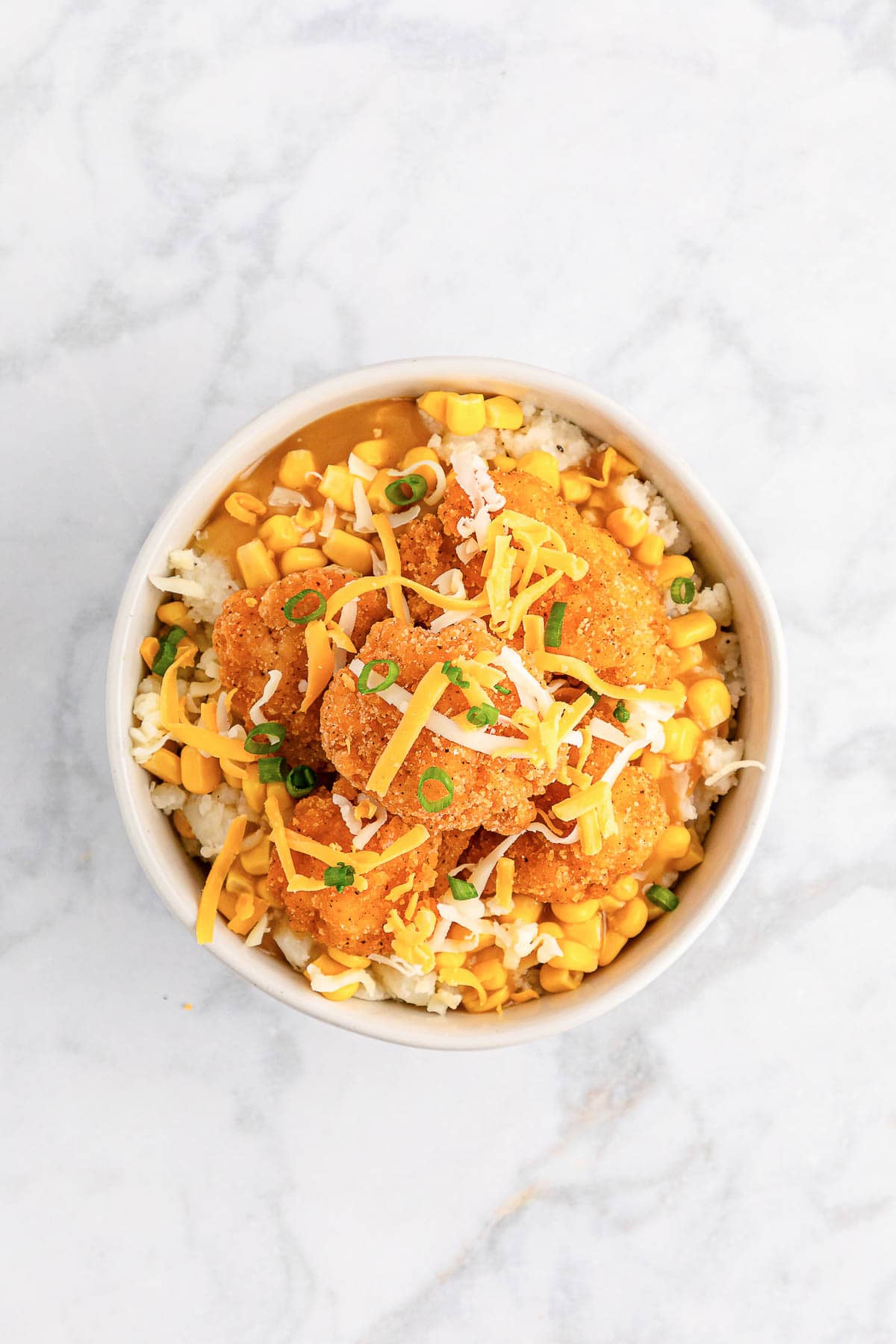 Copycat KFC famous bowl topped with shredded cheese and green onions