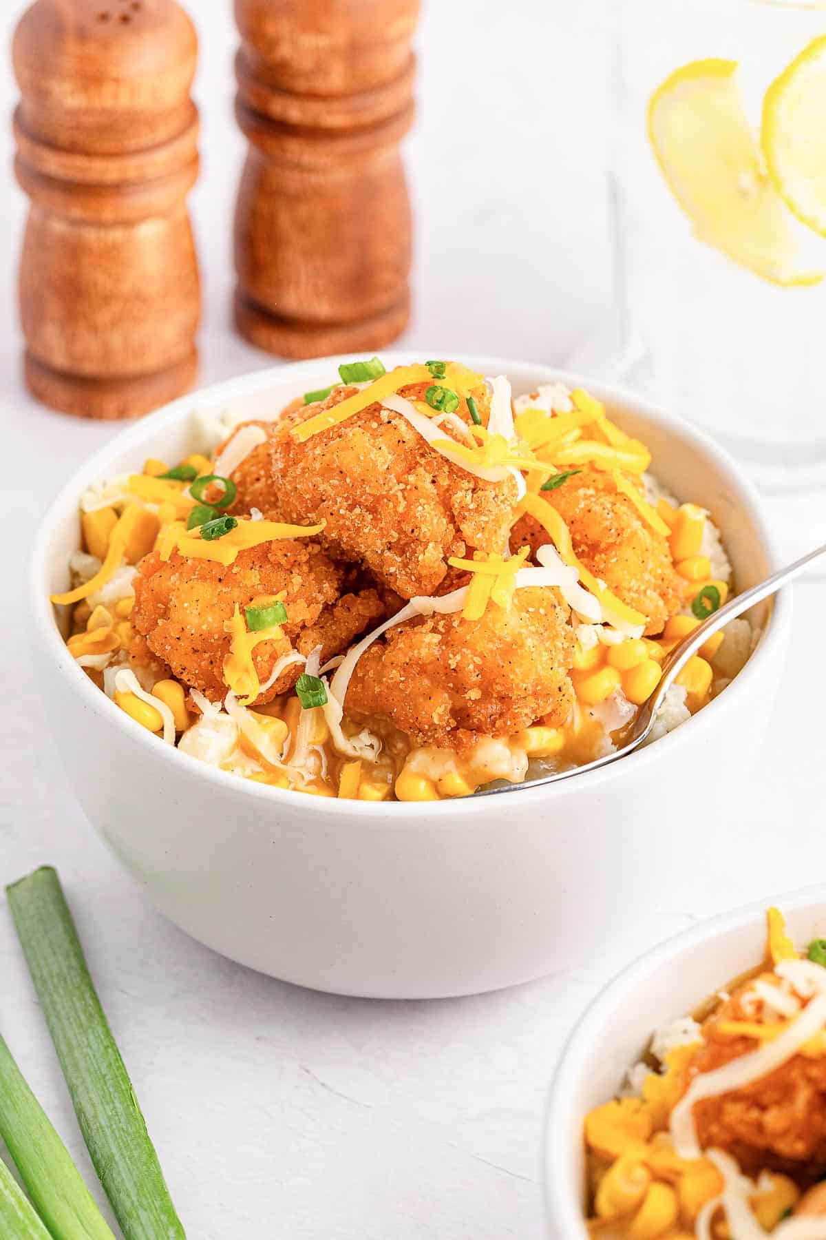 A homemade KFC famous bowl topped with cheddar cheese and green onions.