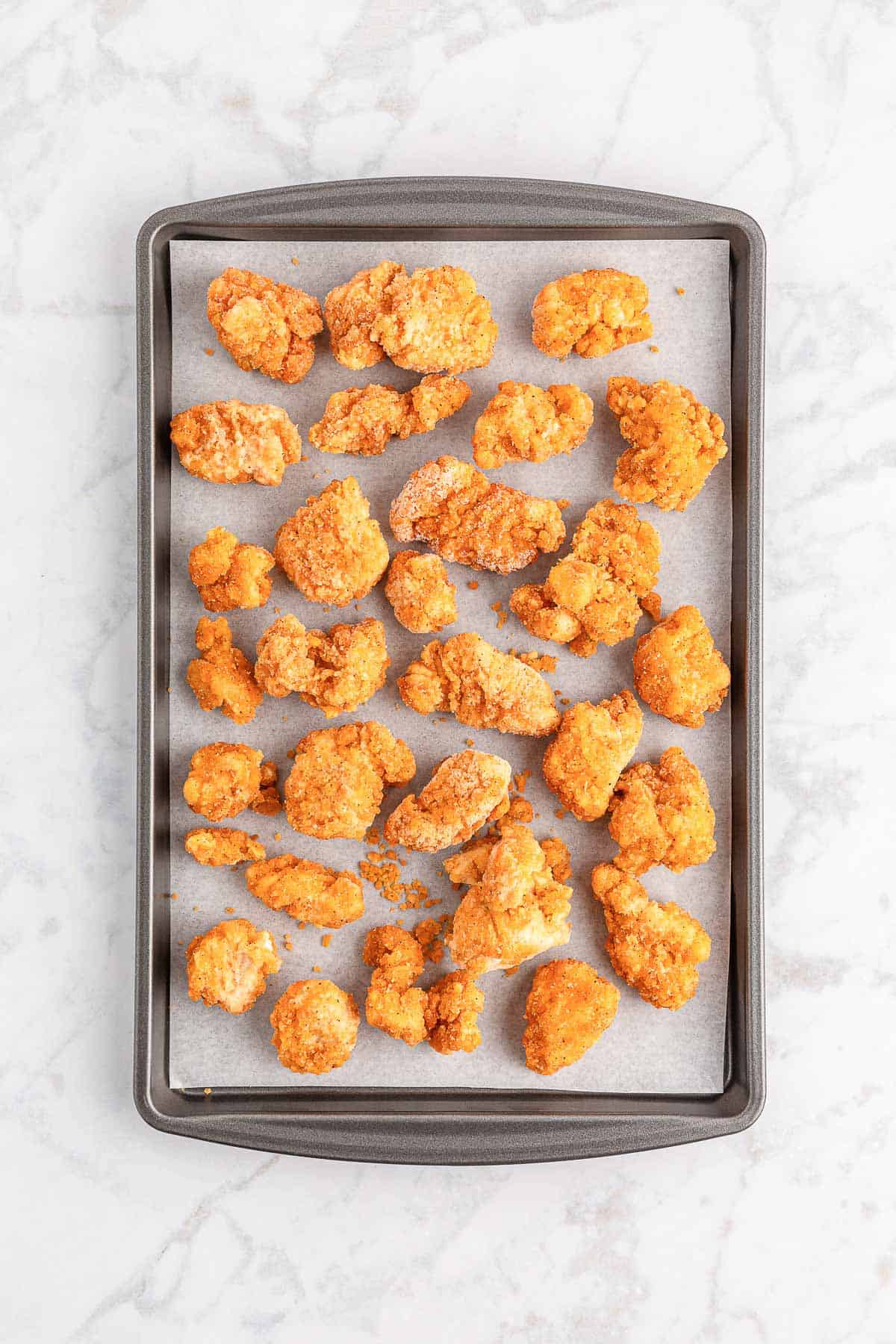 Frozen popcorn chicken on a baking tray.