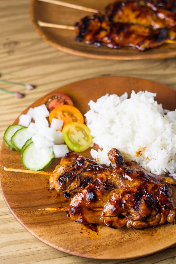 Filipino chicken barbecue skewered and served on a plate with rice and vegetables