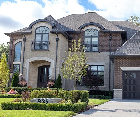 Front of house in stone and brown bricks with landscape in front