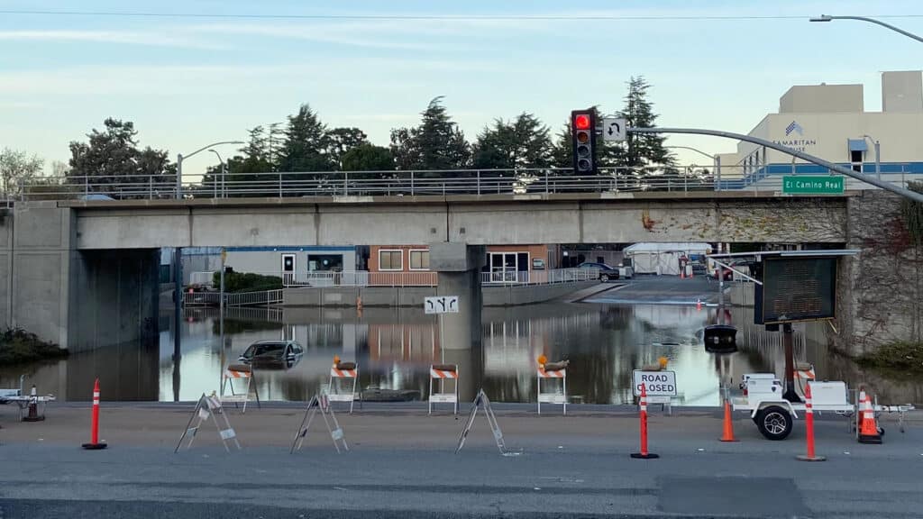 Road closed and car trapped in flooded street under highway underpass