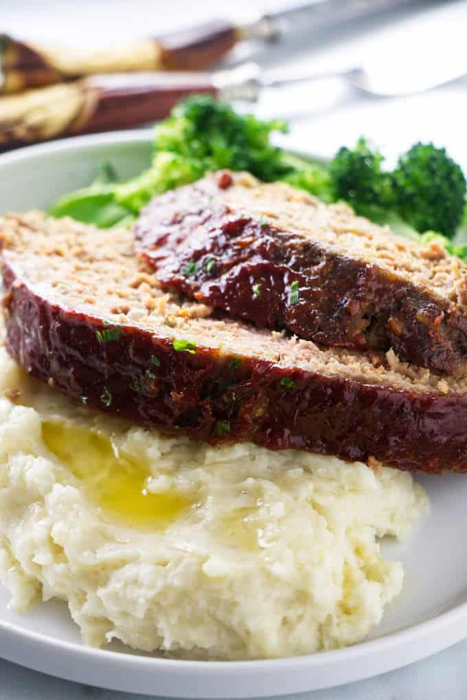 Slices of meatloaf on a plate with broccoli and potatoes.