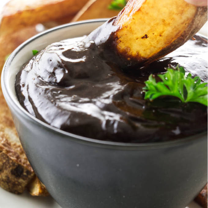 Dipping French fries in a dish of black garlic aioli.