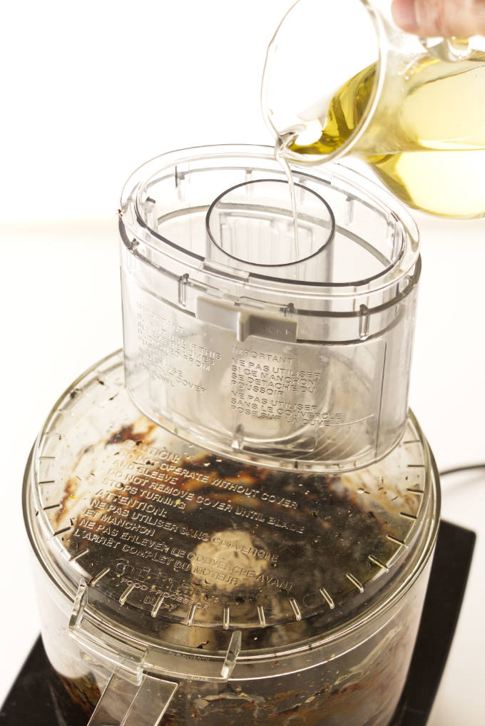 Pouring oil in a food processor to make black garlic aioli.