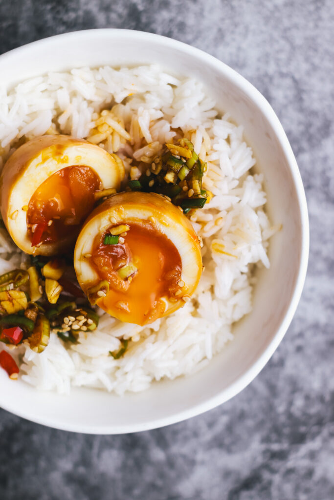 korean boiled eggs cut in half in a bowl with rice